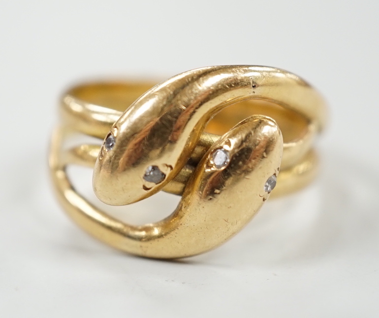 A yellow metal twin shank, two headed entwined serpent ring, with diamond chip set eyes size N/O, gross weight 6.2 grams.